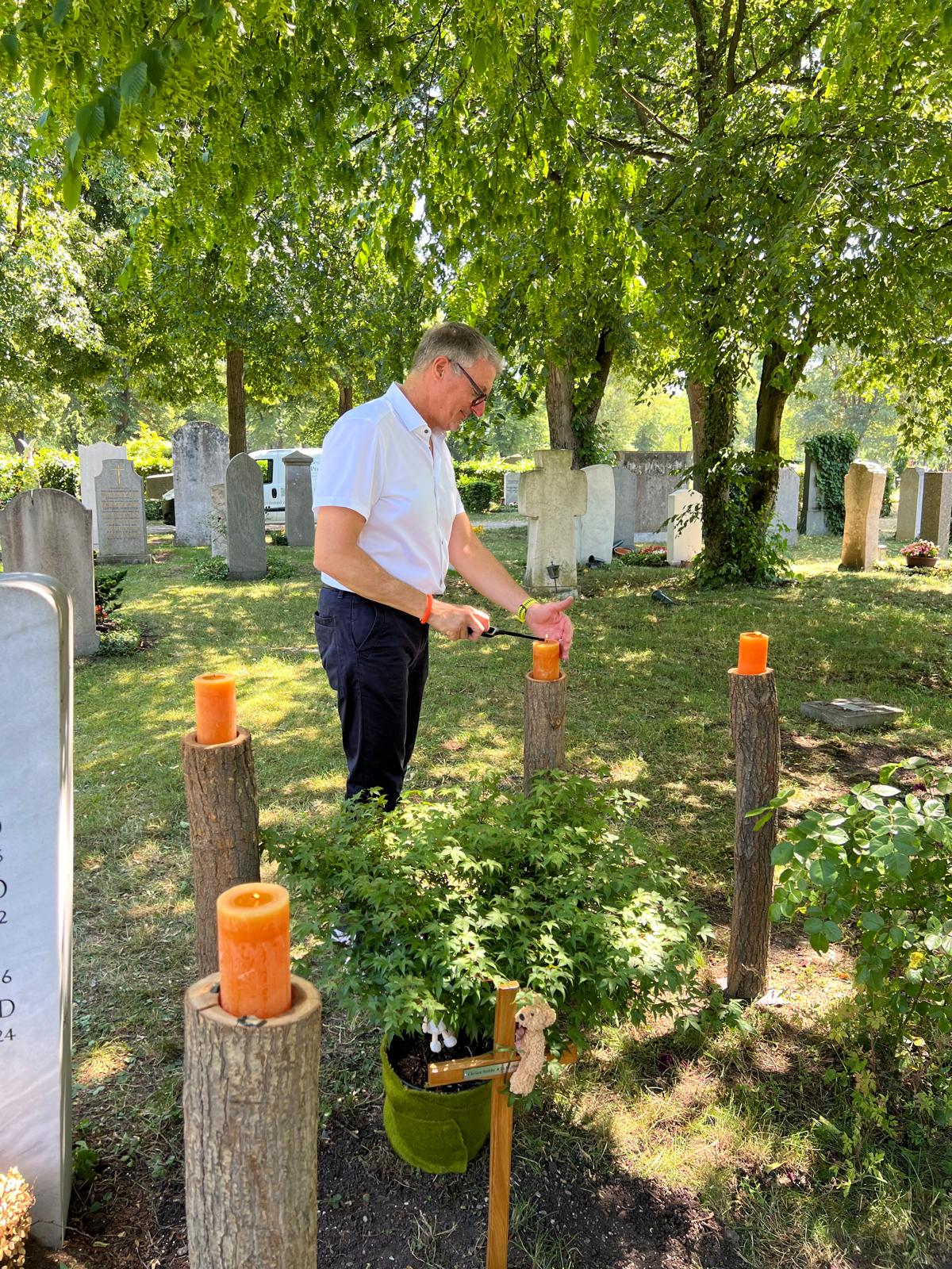 Thomas Poschner entzündet Kerzen auf einem Friedhof während einer Trauerfeier