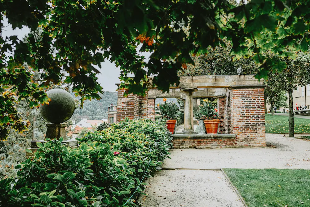 epflegte Gartenanlage mit historischer Backsteinpergola und Steinsäulen – Bestattung Poschner München