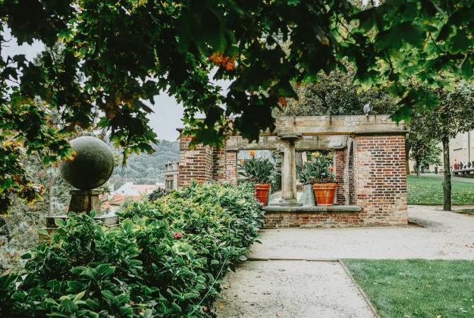 epflegte Gartenanlage mit historischer Backsteinpergola und Steinsäulen – Bestattung Poschner München